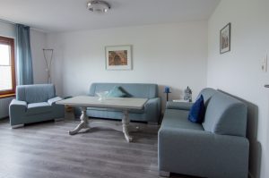 Wohnzimmer mit drei Sofas in hellem blau und einem Couchtisch.